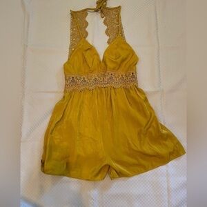 Love Tree mustard colored open back halter romper with crochet detail.